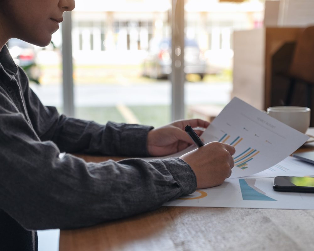 A businesswoman writing and working on business data and document on the table in office